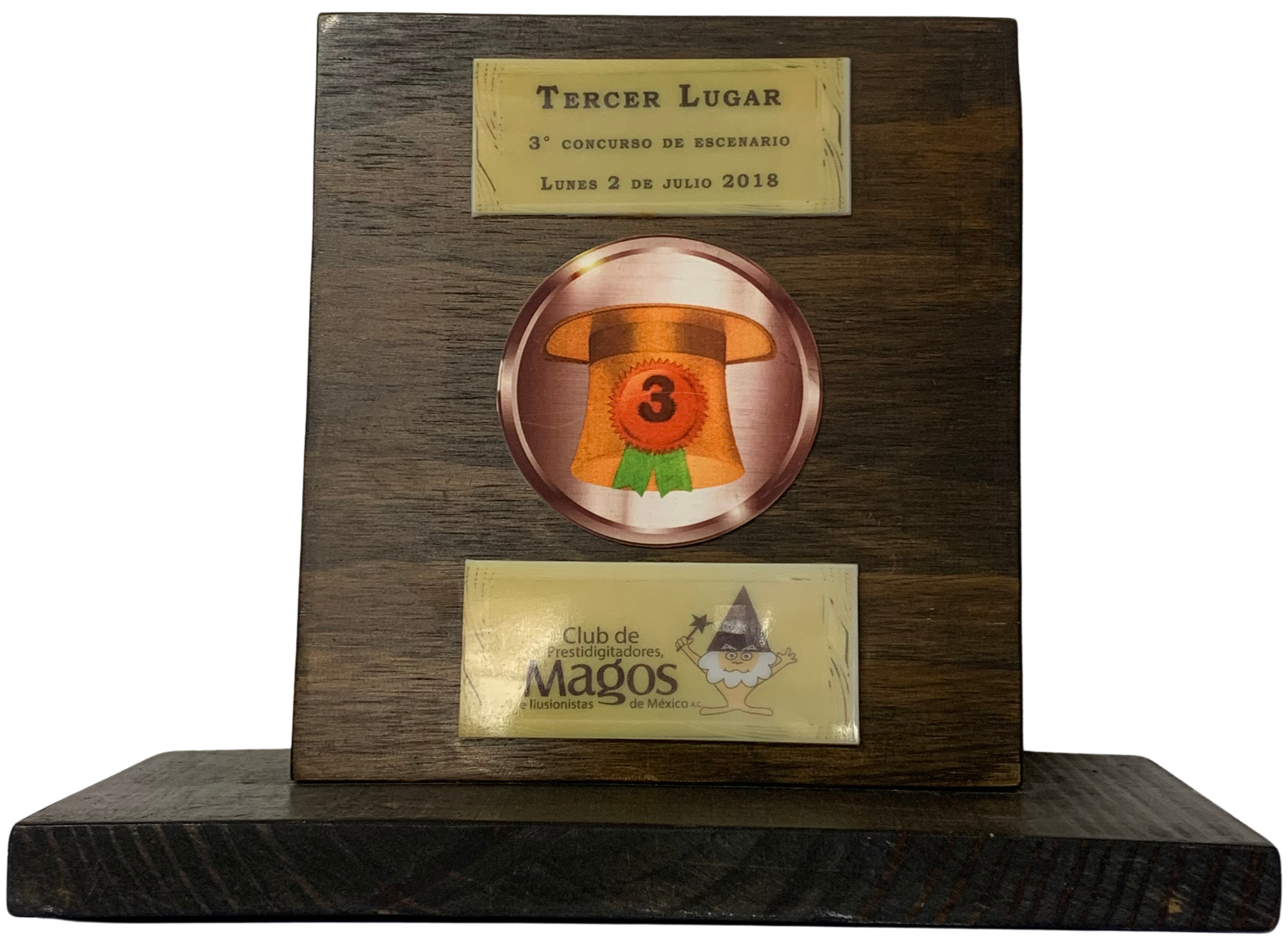 Placa de madera con emblema y placas metálicas, otorgada como 3er lugar en el Concurso de Escenario 2018 por el Club de Prestidigitadores, Magos e Ilusionistas de México