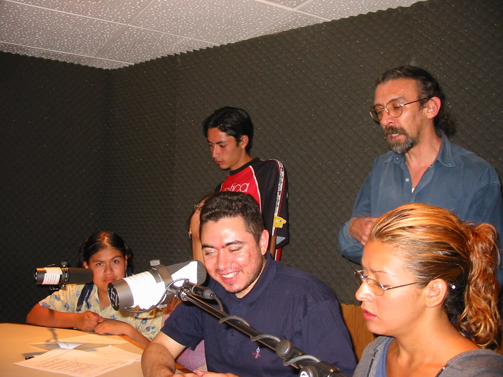 Fotografía de Santiago Salvador González y Ezequiel de la Parra en un estudio de grabación, con micrófonos y colegas alrededor durante la transmisión del programa “La Casa”.